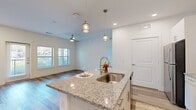 This well-appointed 2-bedroom, 2-bathroom residence offers a thoughtfully designed single-level layout with modern finishes throughout. The open-concept kitchen and living area serves as the heart of the home, anchored by a granite-topped island with an undermount sink and stylish pendant lighting. The kitchen is equipped with stainless steel appliances, white shaker cabinetry, and a classic subway tile backsplash. The adjacent living room features wood-style plank flooring, a ceiling fan, and large windows with outdoor views, filling the space with natural light. A private balcony door extends the living area outdoors. Both bedrooms are generously proportioned, featuring wood-style flooring, ceiling fans, and ample natural light from well-placed windows. The primary bedroom offers direct access to an en-suite bathroom finished with a granite vanity, white cabinetry, and a glass-enclosed walk-in shower with marble-style tile surround. The second bathroom features a shower-tub combination and matching wood-style flooring. Each bedroom is complemented by its own closet, and a dedicated laundry area with in-unit washer hookup adds everyday convenience. The clean white palette and consistent finishes create a bright, cohesive ambiance throughout the entire residence.