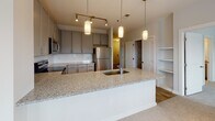 This single-floor residence is thoughtfully designed with a clean, contemporary aesthetic carried throughout each space. The kitchen serves as a central highlight, featuring grey shaker-style cabinetry, white subway tile backsplash, and granite countertops extending across both the perimeter surfaces and a generously sized island with an undermount sink. Pendant lighting illuminates the island, while a full suite of stainless steel appliances—including a refrigerator, range, microwave, and dishwasher—completes the space. Light hardwood-style flooring runs through the kitchen and connecting hallway, contributing to a bright, cohesive look.

The bedrooms are finished with plush carpeting and feature multiple windows with blinds that allow natural light to fill each room. Both walk-in closets are equipped with wire shelving systems, offering organized and practical storage. The primary bathroom includes a dual-sink vanity topped with granite, grey cabinetry with brushed nickel hardware, and large-format tile flooring. A separate tub and shower combination with white subway tile adds a classic finishing touch. The hallway connecting all areas is clean and well-lit, reinforcing the home's bright, neutral palette throughout.