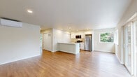 Located at 514 46th St SE in Everett, WA, this thoughtfully designed 2-bedroom, 2-bathroom unit offers a clean, modern aesthetic throughout its single-floor layout. Warm luxury vinyl plank flooring runs continuously through the living spaces, creating a cohesive and inviting atmosphere. The open-concept kitchen and living area serves as the heart of the unit, where a peninsula with a light stone countertop and integrated sink provides both workspace and casual seating. The kitchen is equipped with white shaker-style cabinetry, stainless steel appliances including a refrigerator, electric range, and over-the-range microwave, and recessed lighting overhead. A corner window in the kitchen and dining area fills the space with natural light and greenery views. The living room features a wall-mounted mini-split system for year-round climate control and opens to a private balcony overlooking a landscaped parking area flanked by mature evergreen trees. Both bedrooms are generously proportioned with LVP flooring, recessed lighting, and built-in closets. The primary bedroom includes a spacious closet and an en-suite bathroom with a walk-in shower, while the second bathroom features a full tub-shower combo — both finished with clean white surrounds and wood-tone flooring.