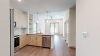 Located at 125 S Standridge Blvd in Anna, TX, this well-appointed 2-bedroom, 2-bathroom residence offers a thoughtfully designed single-floor layout with a clean, contemporary aesthetic. The open-concept kitchen and living area serves as the heart of the home, featuring light wood cabinetry, granite countertops, stainless steel appliances—including a French door refrigerator, electric range, microwave, and dishwasher—and pendant lighting over the kitchen island. Wood-look plank flooring flows throughout the main living areas, adding warmth and continuity. The living room is bathed in natural light from large windows and French doors, and is equipped with a ceiling fan for added comfort. Both bedrooms are carpeted and include ceiling fans and windows with blinds, providing a cozy and quiet retreat. The primary bedroom features a spacious walk-in closet with built-in shelving and a dedicated hanging rod. The primary bathroom offers a granite-topped double vanity with light wood cabinetry, and a glass-enclosed shower. The secondary bathroom includes a dual-sink granite vanity and a tiled shower-tub combo. A second walk-in closet provides additional storage. The overall ambiance is bright, clean, and modern throughout.