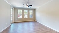 This single-floor residence in Indianapolis offers a thoughtfully designed layout across two bedrooms and two bathrooms. The open-concept kitchen and living area serves as the heart of the home, featuring warm hardwood-style flooring, crown molding, and a ceiling fan with ample natural light from a bank of three windows. The kitchen is well-equipped with gray-toned shaker cabinetry, stainless steel appliances, a white subway tile backsplash, and a striking blue kitchen island topped with white countertops and illuminated by pendant lighting. A glass door leads to an outdoor balcony, extending the living space. The primary bedroom is carpeted and connects directly to an en-suite bathroom with wood-toned cabinetry, white countertops, and an adjoining walk-in closet featuring built-in shelving and dual hanging rods. The second bathroom includes a tub-shower combination clad in white subway tile with matte black fixtures and hardwood-style flooring. The second bedroom is also carpeted with neutral walls. Throughout the space, a consistent palette of neutral tones, matte black hardware, and clean finishes creates a cohesive, modern aesthetic.