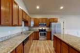Located at 1100 Hunters Run Dr in Grand Blanc, Michigan, this two-story home offers a thoughtfully designed layout with two bedrooms, two bathrooms, and a versatile mix of living spaces spread across two floors. The main level serves as the heart of the home, featuring a kitchen outfitted with warm honey-toned cabinetry, granite countertops, a central island, stainless steel appliances, and light hardwood flooring that flows throughout. Vaulted ceilings add a sense of height and openness to this area, which connects seamlessly to the combined dining and living space. A den and a dedicated office provide additional flexible spaces for work or leisure. The spacious primary bedroom benefits from an arched window that fills the room with natural light, while a generously sized walk-in closet with built-in wire shelving provides ample storage. The bathrooms are finished with tile flooring, a walk-in tiled shower, dark-stained vanities, and polished fixtures. The laundry room includes a full-size washer and dryer. A balcony extends outdoor living opportunities, and the attached garage offers convenient enclosed parking. Wood-look stair treads with a warm wooden handrail connect the two floors with style and practicality.