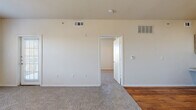 Located in San Antonio, TX, this one-bedroom, one-bathroom unit offers a practical and well-organized single-floor layout. The open living area features neutral-toned carpet, a ceiling fan, and a large window alongside a glass-panel door that leads out to a private balcony, filling the space with natural light and outdoor views. The kitchen is equipped with warm hardwood flooring, ample white cabinetry with wood trim, a double sink, dishwasher, and a white range — providing all the essentials for everyday cooking. The bedroom is a comfortable, carpeted retreat featuring two windows that invite natural light and greenery views, along with a ceiling fan for added comfort. The full bathroom includes a wide vanity with wood-accented cabinetry, a large mirror, tiled shower/tub combo, and direct access to a walk-in closet with built-in shelving. A second closet provides additional storage. An in-unit laundry area adds convenience to daily routines. Throughout the unit, a consistent neutral color palette, clean white trim, and a mix of hardwood and carpet flooring create a cohesive and functional living environment.