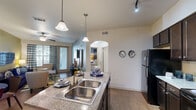Located at 444 E Renfro St in Burleson, TX, this single-story, one-bedroom, one-bathroom residence offers a thoughtfully designed layout that maximizes comfort and functionality. The open-concept living and kitchen area forms the heart of the home, where rich hardwood-style flooring flows throughout. The kitchen is a standout feature, showcasing dark espresso cabinetry, granite countertops, black appliances including a range, microwave, and refrigerator, and a central island with pendant lighting and bar seating — ideal for both cooking and casual dining. The living room is bright and welcoming, with large windows and a sliding glass door that invite natural light and outdoor views, complemented by a ceiling fan overhead. The bedroom offers plush carpeting, a ceiling fan, and a boldly accented feature wall, creating a cozy and restful retreat with access to a dedicated closet. The bathroom is clean and functional, featuring hardwood-style flooring, a tub-shower combination, a dark-toned vanity with a light countertop, and tasteful wall décor. A hallway connects the spaces with ease. Throughout the residence, ceiling fans, warm lighting, and consistent finishes contribute to a cohesive and inviting ambiance.