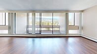 Located at 1552 Esquimalt Avenue in the sought-after community of West Vancouver, BC, this efficiently designed unit offers a well-organized single-floor layout comprising a living room, kitchen, hallway, and bathroom. The living area is the standout feature of the space, highlighted by dramatic floor-to-ceiling windows that span nearly the entire exterior wall, flooding the interior with abundant natural light and framing sweeping views of the surrounding mountains and lush treeline. Warm hardwood flooring runs throughout the living and hallway areas, lending a clean and cohesive aesthetic to the space. The kitchen is thoughtfully appointed with white cabinetry, granite-look countertops, and white appliances including a coil-top electric range with overhead ventilation — a practical and tidy workspace. The bathroom features tile flooring and a full soaker tub-shower combination with white tile surround, offering a clean and functional finish. Neutral wall tones and a textured ceiling complete the interior palette, creating a bright and understated ambiance throughout. The expansive glazing and access to an exterior balcony further enhance the connection to West Vancouver's stunning natural surroundings, making this a uniquely light-filled and view-oriented space.