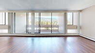 Located at 1552 Esquimalt Avenue in the sought-after community of West Vancouver, BC, this efficiently designed unit offers a well-organized single-floor layout comprising a living room, kitchen, hallway, and bathroom. The living area is the standout feature of the space, highlighted by dramatic floor-to-ceiling windows that span nearly the entire exterior wall, flooding the interior with abundant natural light and framing sweeping views of the surrounding mountains and lush treeline. Warm hardwood flooring runs throughout the living and hallway areas, lending a clean and cohesive aesthetic to the space. The kitchen is thoughtfully appointed with white cabinetry, granite-look countertops, and white appliances including a coil-top electric range with overhead ventilation — a practical and tidy workspace. The bathroom features tile flooring and a full soaker tub-shower combination with white tile surround, offering a clean and functional finish. Neutral wall tones and a textured ceiling complete the interior palette, creating a bright and understated ambiance throughout. The expansive glazing and access to an exterior balcony further enhance the connection to West Vancouver's stunning natural surroundings, making this a uniquely light-filled and view-oriented space.