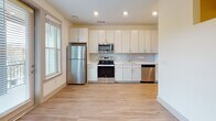 Located at 1001 Boopa Ln in Mount Pleasant, South Carolina, this single-floor residence offers a clean, modern aesthetic throughout. A well-proportioned hallway with recessed lighting and light wood-tone flooring serves as the spine of the unit, connecting the various living areas with a sense of order and flow.

The kitchen is a standout feature, outfitted with a full suite of stainless steel appliances including a refrigerator, electric range, built-in microwave, and dishwasher. Crisp white cabinetry extends to the ceiling, maximizing storage, while a subway tile backsplash and light countertops add a contemporary, polished finish. Recessed lighting illuminates the space efficiently.

The living area is bright and open, benefiting from natural light that filters through multiple windows. A ceiling fan keeps the space comfortable, and a glass-panel door opens to an outdoor balcony, offering views of surrounding greenery — a notable feature for enjoying the mild South Carolina climate.

The bathroom is finished in a clean, minimalist style, featuring a glass-enclosed walk-in shower with chrome fixtures, wood-look flooring, and white walls that create a fresh, spa-like atmosphere.

Throughout the unit, consistent light wood flooring, neutral wall tones, and recessed lighting create a cohesive, modern living environment suited to a variety of lifestyles.