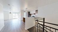 Located at 9675 Avenue Papineau in Montréal, this modern two-storey unit offers a well-designed layout spread across two floors. The upper level welcomes you with an open-concept kitchen and living area bathed in natural light from large windows. The sleek kitchen features two-tone cabinetry in white and charcoal grey, warm wood shelving accents, a marble-effect tile backsplash, stainless steel appliances, and a peninsula island with built-in wine storage and pendant globe lighting — ideal for both cooking and entertaining. The living area flows seamlessly from the kitchen, with access to a balcony via a full-length window. Light hardwood flooring runs throughout both levels, complementing the clean white walls and modern aesthetic. The lower floor includes a hallway entry, the primary bedroom, and a second versatile room with a small window and baseboard heating. The bedroom is a comfortable size with a sliding-door closet, while a separate walk-in closet provides generous additional storage. The full bathroom is well-appointed with a soaking tub, separate glass-enclosed shower, a wood-framed floating vanity with vessel sink, and warm taupe tile accents. A mini-split climate system adds year-round comfort to this thoughtfully finished Montréal residence.