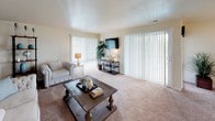 Located at 4085 Warner Ave in Landover Hills, Maryland, this single-floor apartment offers a thoughtfully designed layout with distinct living, dining, sleeping, and kitchen areas. The galley-style kitchen features warm wood cabinetry, granite-look countertops, tile flooring, and full appliances including a gas range, dishwasher, and refrigerator — providing ample prep and storage space. The open living room is a standout, highlighted by a bold teal accent wall, plush carpet, and large sliding glass doors with vertical blinds that allow generous natural light and outdoor views. A dedicated dining area adjacent to the living space includes a ceiling fan and a window, creating an inviting setting for meals. The primary bedroom is generously sized with soft carpet, a large closet with built-in shelving, and direct access to the hallway. A secondary bedroom features carpet flooring, a window with natural light, and comfortable proportions. The full bathroom is finished with tile flooring, a tub-shower combination, a window for ventilation, and clean neutral tones throughout. Overall, the unit presents a warm, functional, and comfortable living environment suited for everyday residential use.