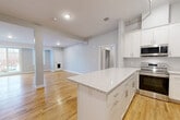This well-appointed 2-bedroom, 2-bathroom residence in Danvers, MA offers a thoughtfully designed single-floor layout with a bright, open-concept living space. The kitchen serves as the centerpiece, showcasing white shaker cabinetry, a granite-topped center island, and a full suite of stainless steel appliances including a refrigerator with ice maker, range, and microwave. Light hardwood flooring flows throughout the main living areas, complementing the neutral gray walls and recessed lighting overhead.

The living room extends naturally from the kitchen, bathed in natural light from large windows and a glass door that opens to a balcony, offering outdoor views. Both bedrooms feature plush carpeting and ample closet space — notably, the space includes seven closets throughout, providing generous storage. The primary bedroom benefits from large windows that invite natural light.

The two bathrooms are finished with consistent, clean aesthetics: white vanities topped with granite counters, tile flooring, and a full tub-shower combo in the main bath. A dedicated laundry area and two hallways add to the unit's functional layout, making this a well-organized and move-in-ready home.