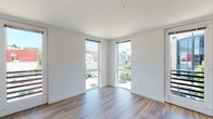 Located on the fifth floor at 429 2nd Avenue West in Seattle's Queen Anne neighborhood, this modern unit offers a thoughtfully designed single-level layout with clean lines and a bright, contemporary aesthetic throughout. Warm hardwood-style flooring extends seamlessly across every room, creating a cohesive and inviting atmosphere.

The open living area is bathed in natural light from large floor-to-ceiling windows and a glass door that frames views of the surrounding Seattle cityscape and neighboring rooftops. Corner window placement in the living space maximizes light and provides a panoramic perspective of the neighborhood.

The kitchen is efficiently designed with flat-front light wood cabinetry, light quartz countertops, a stainless steel sink with a modern pull-down faucet, and a full suite of stainless steel appliances including a range, over-the-range microwave, refrigerator, and dishwasher. A tile backsplash adds a clean, finished look.

The bedroom is a well-proportioned, quiet retreat featuring a large window with views and a sliding closet door. The bathroom continues the modern design language with light wood vanity cabinetry, a white countertop, and plantation shutters offering privacy while allowing natural light. The unit's crisp white walls and recessed lighting throughout reinforce its clean, contemporary character.
