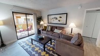 Located at 9415 N 99th Ave in Peoria, Arizona, this single-story residence offers a well-organized layout designed for comfortable everyday living. The living room serves as the heart of the home, featuring a textured ceiling, warm ambient lighting, and a sliding glass door that opens to a private outdoor patio — allowing natural light to flow freely into the space. The kitchen is outfitted with sleek grey cabinetry, light countertops, wood-look flooring, and black appliances, providing a functional and modern cooking environment. Adjacent to the kitchen, a dedicated dining area offers an intimate setting with decorative wall accents and space for a round dining table. Two bedrooms provide restful retreats, each featuring plush carpeting, ceiling fans with integrated lighting, and windows that bring in views of the surrounding neighborhood. One bedroom benefits from a walk-in closet and direct access to the bathroom. The bathroom includes a combination tub and shower with a stainless steel grab bar, emphasizing accessibility and safety. Throughout the home, a neutral color palette and consistent design choices create a cohesive and inviting atmosphere well-suited to the sunny Peoria, Arizona lifestyle.