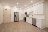 Located at 15123 Brookhurst St in Westminster, California, this single-story unit offers a clean, modern aesthetic throughout its thoughtfully designed layout. The kitchen is a standout feature, showcasing crisp white shaker cabinetry with gold-toned hardware, white quartz countertops, a subway tile backsplash, and a full suite of stainless steel appliances including a French door refrigerator, electric range, over-the-range microwave, and dishwasher. Light wood-look flooring runs through the kitchen and entry area, lending warmth to the bright, recessed-lit space. The entry is secure and modern, complementing the unit's contemporary finishes. The living area is open and airy, offering a generous footprint with a large window that brings in natural light. The bedroom features plush carpeting and direct access to a walk-in closet with built-in shelving, providing ample storage. The full bathroom is finished with light flooring, a white vanity, a bathtub, and matte black hardware and grab bars for added accessibility. Completing the unit is a dedicated laundry area with a stacked Whirlpool washer and dryer, adding everyday convenience to this well-appointed space.