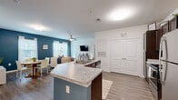 This well-appointed 2-bedroom, 2-bathroom single-floor residence at 1000 Channel Marker Way in Hanahan, SC offers a comfortable and functional layout. The open-concept living area serves as the heart of the home, where the kitchen, dining, and living rooms flow seamlessly together. The kitchen features dark espresso cabinetry, stainless steel appliances, and a granite-topped peninsula with an integrated sink, providing both prep space and a casual bar area. The adjacent dining space is bathed in natural light from a large window and is accented by a bold teal feature wall. The living room continues the teal accent wall, complemented by wood-look flooring, a ceiling fan, and multiple windows with sheer curtains that invite natural light. Both bedrooms are carpeted and feature windows for natural light. The primary bedroom includes access to a spacious walk-in closet outfitted with wire shelving systems. Each bathroom is finished with tile flooring and dark vanity cabinetry, with a tub-shower combination. Two dedicated closets throughout the home provide ample storage. The overall design palette of neutral whites, warm wood tones, and teal accents creates a cohesive and inviting atmosphere throughout.