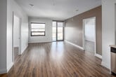 This penthouse unit at 460 Belmont Ave W in Kitchener presents a thoughtfully designed two-bedroom, two-bathroom layout with a clean, contemporary aesthetic throughout. Light-toned laminate wood flooring flows continuously across the main living areas, complementing the bright white walls and creating a cohesive, modern feel.

The open-concept kitchen is a standout feature, showcasing white shaker-style cabinetry extending to the ceiling, a subway tile backsplash, stainless steel appliances including a built-in microwave, electric range, dishwasher, and refrigerator, and a generous island with a light countertop that doubles as a breakfast bar. The kitchen transitions seamlessly into the living area, which benefits from large floor-to-ceiling windows and a glass door that flood the space with natural light while offering elevated views of the cityscape.

The bedrooms are finished with the same light laminate flooring and feature windows that continue the penthouse's bright character. The primary bathroom includes a sleek glass-enclosed walk-in shower with tile surround, while the second bathroom offers a full soaker tub with tiled walls. A dedicated closet and clean, neutral finishes throughout contribute to the unit's polished, move-in-ready presentation.