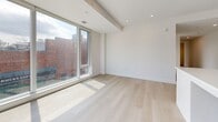 Located at 200 Elgin Street in the heart of Ottawa, this modern 2-bedroom, 2-bathroom unit offers a well-designed single-floor layout with clean contemporary finishes throughout. The open-concept living and kitchen area serves as the centrepiece of the home, featuring light hardwood flooring, recessed lighting, and a striking bank of floor-to-ceiling windows that frame views of the surrounding cityscape and historic neighbourhood architecture. The kitchen is outfitted with grey cabinetry, white subway tile backsplash, stainless steel appliances including a full-size refrigerator and gas range, a central island, and stylish pendant lighting overhead.

Both bedrooms are bright and airy, benefiting from large windows that flood each room with natural light and offer urban views. The primary bedroom includes a sliding closet and direct access to an ensuite bathroom. The second bedroom features a built-in closet with rod storage. Both bathrooms are finished with large-format beige tile flooring, white vanities with matte black hardware, and glass-enclosed walk-in showers with marble-style tile surrounds. A hallway connects the main living areas to the private bedroom wing, creating a functional and cohesive flow throughout the space.