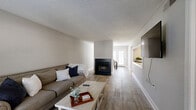 Located at Windsor Green in Goodlettsville, TN, this two-bedroom, two-bathroom residence offers a well-organized single-floor layout designed for comfortable everyday living. The living room features wood-look flooring, a classic fireplace with a black surround, and a large window that draws in natural light, creating a warm and inviting atmosphere. Adjacent to the living area, the dining room is accented by a pendant light fixture and includes direct access to a private outdoor balcony with exterior views. The galley-style kitchen is well-appointed with dark cabinetry, marble-style countertops, a subway tile backsplash, and stainless steel appliances, including a refrigerator and electric range. Both bedrooms are carpeted and offer windows that provide natural light. The primary bedroom is generously sized, while the second bedroom is comfortably scaled for guests or a home office. Each bathroom features wood-look tile flooring and shower-tub combinations — one with dark cabinetry and gold-toned fixtures, and the other with a clean, minimal design. Neutral gray tones and textured ceilings run throughout the residence, lending a cohesive and understated aesthetic across all rooms.