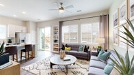 This thoughtfully designed single-floor residence offers a seamless blend of modern style and comfortable living. The entry opens into a welcoming foyer, complete with a built-in hook station, leading directly into the spacious living area. The living room is bathed in natural light streaming through large windows dressed with blinds and drape curtains, and is anchored by a ceiling fan overhead. Built-in shelving adds functional character, while a sliding glass door provides access to a private outdoor patio area. The kitchen is outfitted with crisp white cabinetry, granite-style countertops, a subway tile backsplash, and a full suite of stainless steel appliances including a refrigerator, range, microwave, and dishwasher. The bedroom features a soothing two-tone paint scheme, dual windows for natural light, and direct access to a well-sized closet. The primary bathroom includes a walk-in glass-enclosed shower with large-format tile surround, while a separate half bath offers a granite-topped vanity and wood-look flooring. Wood-look flooring flows consistently throughout the residence, tying together a cohesive, contemporary aesthetic. The overall ambiance is bright, clean, and modern.