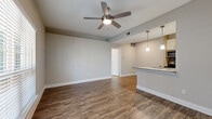 Located at 4146 Scone St in Houston, Texas, this single-floor residence offers a well-designed layout with consistent wood-look flooring throughout, creating a cohesive and warm aesthetic across every room. The open living area is bright and airy, featuring a ceiling fan and natural light streaming through large windows dressed with classic white blinds. A front entry door with sidelights further enhances the sense of openness.

The kitchen is a standout feature, outfitted with stainless steel appliances including a range, microwave, refrigerator, and dishwasher. White shaker-style cabinetry with brushed nickel hardware lines the walls, complemented by granite countertops and a dark tile backsplash. A central island with a built-in sink and pendant lighting above serves as a practical and stylish focal point that connects the kitchen to the living space.

The bedrooms are generously sized, each equipped with ceiling fans and windows that invite natural light. The bathroom features a granite-topped vanity with white cabinetry, a tub-shower combination with white tile surround, and hardwood-style flooring. Storage is plentiful, with multiple walk-in closets outfitted with wire shelving systems offering flexible organization. A dedicated laundry area is also present within the unit.