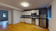Located at 32 High St in the heart of New Haven, CT, this one-bedroom, one-bathroom unit offers a thoughtfully designed single-floor layout. Warm hardwood floors run throughout the living spaces, lending a classic and cohesive feel to the interior.

The kitchen is well-appointed with white shaker-style cabinetry, dark countertops, a gray tile backsplash, and a full suite of stainless steel appliances including a gas range, built-in microwave, dishwasher, and refrigerator. The open configuration allows the kitchen to flow naturally into the adjacent living area, maximizing usability.

The bedroom is bright and generously proportioned, featuring crown molding, hardwood floors, and a closet with built-in rod storage. A distinctive architectural highlight of the bedroom is the pair of stained glass windows, which add character and visual interest with colorful heraldic designs — a nod to the building's historic roots in New Haven.

The bathroom is equipped with a full soaking tub and shower combination, fitted with stainless steel grab bars for added accessibility and safety.

Overall, this unit balances modern updates with charming original details, making it a practical and characterful home in a prime New Haven location.