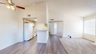 Located in Tucson's 85749 zip code, this single-story, two-bedroom, one-bathroom home offers a thoughtfully arranged floor plan that maximizes its compact footprint. The open-concept living and kitchen area is anchored by soaring vaulted ceilings that lend a sense of spaciousness well beyond the unit's modest size. Durable hardwood-style flooring runs through the kitchen and main living area, while plush carpet covers the living room and bedrooms.

The kitchen features light wood cabinetry, white appliances including a refrigerator, oven, and dishwasher, and a skylight that fills the galley-style space with natural light. A peninsula counter separates the kitchen from the main living area, which includes a fireplace framed in tile — a standout feature that adds warmth and character. Large sliding glass doors and a arched accent window invite abundant natural light into the living space.

Both bedrooms are carpeted and offer windows with views of the surrounding landscape. One bedroom includes a dedicated closet with shelving. The shared bathroom features light wood cabinetry, a single vanity with a large mirror, hardwood-style flooring, and a tub-shower combination. A hallway connects the private areas of the home, completing the practical and straightforward layout.