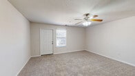 This single-floor, handicap-accessible home in Munford, Tennessee offers a functional and comfortable layout with two bedrooms and two bathrooms. The spacious living room greets you at the entrance, featuring plush carpeting, a ceiling fan with light fixture, and a window that lets in natural light, creating a bright and airy atmosphere. The kitchen is well-equipped with warm oak cabinetry, laminate countertops, white appliances including a refrigerator, electric range, and built-in microwave, all complemented by durable hardwood-style flooring. A convenient breakfast bar separates the kitchen from the adjoining living area, ideal for casual dining. Both bedrooms are carpeted and generously sized, each served by ceiling fans. The primary bedroom features direct access to a dedicated bathroom and a closet, while the second bedroom is bright with a window view. The two bathrooms include a full bath with a tub and shower surround, and a half bath with a single vanity sink and hardwood-style flooring. Neutral tones throughout the home create a clean, move-in ready aesthetic, and the accessible design ensures ease of living for all occupants.