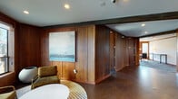 Located at 928 Shorepoint Court in Alameda, California, this single-story commercial space offers a refined and distinctive work environment defined by its consistent use of rich, dark wood paneling throughout. The architectural character is immediately established upon entry, where floor-to-ceiling wood-paneled walls, exposed structural beams, and polished concrete and tile flooring create a warm yet professional atmosphere.

The layout includes multiple private offices, each featuring wood-paneled walls, large windows that invite natural light and outdoor views, patterned blue-toned carpet, and pendant lighting. These offices are well-suited for focused individual work or small group meetings, with built-in desk surfaces in select rooms.

A generously sized conference room serves as a central meeting space, accommodating a large rectangular table surrounded by ergonomic chairs. Rows of framed windows line the walls, filling the room with diffused natural light, while flush-mounted ceiling fixtures provide consistent overhead illumination.

Connecting the rooms is a corridor with polished flooring that transitions between carpeted and hard-surface areas. A kitchenette or breakroom features white cabinetry and built-in appliances, offering a functional support space. Throughout, the recurring wood paneling, exposed beams, and curated artwork contribute to a cohesive, character-rich professional environment.