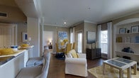 This well-appointed 2-bedroom, 2-bathroom residence is thoughtfully designed to maximize both comfort and functionality across a single floor. The open-concept living and dining area serves as the heart of the home, featuring rich hardwood flooring, crown molding, and recessed lighting that create a refined yet welcoming atmosphere. Large windows dressed with elegant drapes flood the space with natural light and offer views of the outdoors, while a private balcony access adds an additional dimension to the living experience. The living area is generously sized to accommodate a variety of furniture arrangements, seamlessly flowing into a dedicated dining space perfect for entertaining. Warm, neutral-toned walls provide a versatile backdrop that complements a range of décor styles, as reflected in the tasteful use of gold, white, and grey accents throughout. The two bedrooms offer private retreats, each serviced by its own full bathroom for added convenience. The overall ambiance of the residence is one of modern elegance — bright, open, and inviting — making it an ideal space for both everyday living and hosting guests.