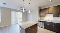 Located at 109 Pearl Ave in the heart of Greenville, SC, this well-appointed single-floor unit offers a thoughtfully designed open-concept layout that maximizes every square foot. The combined kitchen and living area serves as the central hub of the space, featuring light hardwood-style flooring, neutral wall tones, and a ceiling fan that enhances airflow and comfort throughout.

The kitchen is a standout feature, equipped with a full suite of stainless steel appliances including a refrigerator, range, microwave, and dishwasher. Rich dark-espresso cabinetry extends to the ceiling, providing generous storage, while granite countertops add a polished, upscale finish. A granite-topped kitchen island with pendant lighting above offers additional prep space and a casual dining option.

The living area is bright and airy, benefiting from multiple large windows fitted with horizontal blinds that allow for excellent natural light control. A sliding glass door opens directly onto a private balcony with outdoor views of the surrounding Greenville neighborhood.

The bathroom is clean and functional, featuring tile flooring, a full tub/shower combination, a dark-cabinetry vanity with a granite countertop, and a framed mirror. Two closets provide ample storage, and a dedicated laundry area adds everyday convenience to this efficiently designed residence.