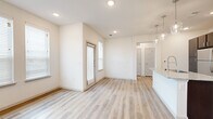 This well-appointed one-bedroom, one-bathroom unit in Waco, TX offers a thoughtfully designed layout across a single floor. The open-concept living and kitchen area is anchored by light wood-look plank flooring and bright white walls, creating a clean, airy atmosphere. Recessed lighting and multiple windows with horizontal blinds allow natural light to fill the space throughout the day.

The kitchen is a standout feature, boasting rich dark espresso cabinetry, granite countertops, a subway tile backsplash, and a full suite of stainless steel appliances including a refrigerator, range, and built-in microwave. A peninsula island with a granite surface and undermount sink adds both functionality and a defined gathering point between the kitchen and living area, illuminated by stylish pendant lighting above.

The bedroom offers plush carpeting, a ceiling fan, and a window that brings in natural light, providing a comfortable and quiet retreat. The closet offers dedicated storage to keep the space organized. The bathroom is finished with the same dark cabinetry and granite countertop, complemented by a tiled tub-shower combination with marble-style tile and a large vanity mirror. Wood-look flooring extends into the bathroom, maintaining a cohesive design aesthetic throughout the unit.