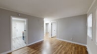 This 2-bedroom, 1-bathroom single-floor unit offers a clean, modern aesthetic with a cohesive design throughout. Warm-toned hardwood-style flooring runs through the main living areas and bedrooms, complemented by neutral gray walls and crisp white trim that create a bright, fresh atmosphere.

The living room is a welcoming, open space featuring multiple windows that invite natural light and baseboard heating for year-round comfort. A white paneled entry door provides direct access to the unit. The kitchen is thoughtfully equipped with white cabinetry, granite-style countertops, a stainless steel sink with a matte black faucet, and stainless steel appliances, including a refrigerator and electric range. Light hardwood-style flooring and a direct sightline into the living area give the kitchen an open, connected feel.

Both bedrooms are comfortably scaled, each featuring neutral gray walls, hardwood-style flooring, baseboard heating, and windows with blinds. One bedroom includes a window-mounted air conditioning unit for added climate control. A secondary entry door is also accessible from one of the bedrooms.

The bathroom is neatly finished with light tile flooring, wainscoting, a combined tub and shower, a pedestal-style sink, and matte black fixtures and accessories. A window with blinds provides ventilation and natural light. The overall layout is efficient and functional, making excellent use of the available space.
