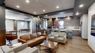Located at 50 Public Square in the heart of Cleveland, Ohio, this generously sized amenity floor offers a sophisticated and well-appointed gathering space designed for both relaxation and entertainment. The open-concept layout is anchored by a stylish lounge area furnished with rich leather sofas, upholstered armchairs, and a wooden coffee table, all set atop warm hardwood-style flooring that runs throughout the space.

A full bar and kitchen area serves as a central hub, featuring dark wood cabinetry, herringbone tile backsplash, pendant lighting, and bar seating with patterned upholstered stools. Built-in appliances and a large refrigerator make this area fully functional for hosting and events. Adjacent to the lounge, a dining and lounge zone offers built-in banquette seating and bistro-style tables, creating an intimate yet open atmosphere.

A dedicated billiards room provides a focal point for recreation, complete with a full-size pool table, shuffleboard table, and city-facing windows that flood the space with natural light. Tiered levels connected by dark wood steps add architectural dimension to the floor plan.

The experience extends outdoors to a spacious rooftop terrace, where patio furniture is set against a striking backdrop of Cleveland's downtown skyline, offering sweeping open-air views under natural light.