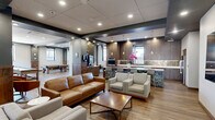 Located at 50 Public Square in the heart of Cleveland, Ohio, this generously sized amenity floor offers a sophisticated and well-appointed gathering space designed for both relaxation and entertainment. The open-concept layout is anchored by a stylish lounge area furnished with rich leather sofas, upholstered armchairs, and a wooden coffee table, all set atop warm hardwood-style flooring that runs throughout the space.

A full bar and kitchen area serves as a central hub, featuring dark wood cabinetry, herringbone tile backsplash, pendant lighting, and bar seating with patterned upholstered stools. Built-in appliances and a large refrigerator make this area fully functional for hosting and events. Adjacent to the lounge, a dining and lounge zone offers built-in banquette seating and bistro-style tables, creating an intimate yet open atmosphere.

A dedicated billiards room provides a focal point for recreation, complete with a full-size pool table, shuffleboard table, and city-facing windows that flood the space with natural light. Tiered levels connected by dark wood steps add architectural dimension to the floor plan.

The experience extends outdoors to a spacious rooftop terrace, where patio furniture is set against a striking backdrop of Cleveland's downtown skyline, offering sweeping open-air views under natural light.