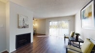 Located at 10853 Rose Ave in the heart of Los Angeles, CA 90034, this single-floor residence offers a well-organized layout with consistent hardwood-style flooring throughout and a textured ceiling that adds character to each room. The living area is a standout space, anchored by a fireplace and large sliding glass doors fitted with vertical blinds that invite abundant natural light and provide direct access to the outdoors. Adjacent to the living area, a defined dining space offers room for a full dining set and is illuminated by a ceiling fan with integrated lighting. A separate, generously sized room with floor-to-ceiling windows serves as a flexible secondary living or bedroom space. The kitchen features white cabinetry, dark countertops, stainless steel appliances including a refrigerator, microwave, and range, and is finished with track lighting for a functional, modern feel. Two bathrooms are present — one with a tub-shower combination and a window for natural ventilation, and another with a walk-in shower, vanity, and wood-look flooring. Additional rooms are bright and neutral, offering versatile use. The overall ambiance is clean, functional, and well-lit, suited for comfortable urban living in West Los Angeles.