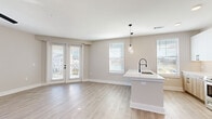 Located at 914 Grays Mill Road in Harrisburg, NC, this well-appointed 2-bedroom, 3-bathroom single-floor home offers a thoughtfully designed open-concept layout with clean, modern finishes throughout. Light-toned luxury vinyl plank flooring flows seamlessly across the entire home, creating a cohesive and contemporary aesthetic.

The combined kitchen and living area serves as the heart of the home, highlighted by a large island with crisp white quartz countertops, an undermount sink, and a matte black pull-down faucet. Stylish pendant lights hang above the island, while multiple windows invite generous natural light. French doors open to an outdoor area, enhancing the sense of openness. Light wood cabinetry with matte black hardware and stainless steel appliances complete the kitchen.

A well-lit hallway with built-in open shelving connects the main living area to the private quarters. The primary bedroom is a comfortable retreat featuring a ceiling fan and a walk-in closet with a full shelving and hanging system. The primary bathroom offers a dual-sink vanity with white quartz countertops, wood-toned cabinetry, matte black fixtures, and a tiled walk-in shower. The secondary bathroom includes a tub-shower combination with vertical tile surround. Each bedroom benefits from natural light and neutral wall tones, contributing to a calm, modern ambiance throughout.