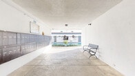Located at 4444 Hazeltine Ave in Sherman Oaks, Los Angeles, this expansive residential community spans a generous footprint across a single level of shared amenity spaces. The entrance greets residents with a covered walkway, a row of individual mailboxes, and a bench seating area, opening directly onto the bright, sunlit courtyard beyond.

The outdoor areas are a true highlight of the property. Multiple landscaped courtyards feature gravel pathways lined with stepping stones, mature palm trees, lush shrubs, and decorative planters. Outdoor barbecue grills and shaded dining areas with umbrella-covered tables provide inviting spaces for gathering, while a gated swimming pool with lounge chairs offers a resort-like retreat. The crisp white exterior of the building, accented with navy blue doors and iron railings, lends a clean, modern aesthetic throughout.

The fitness center is well-appointed with light hardwood flooring, recessed lighting, floor-to-ceiling mirrors, and a comprehensive selection of equipment including treadmills, ellipticals, free weights, resistance tools, and exercise mats — complemented by a mounted TV for entertainment during workouts.

The laundry facility is neatly organized with stacked washer and dryer units, warm hardwood-style flooring, built-in storage cabinetry, and a folding counter, making it both functional and comfortable for everyday use.