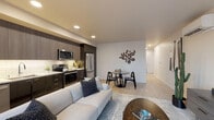 Located at 701 5th Avenue North in Seattle's vibrant Lower Queen Anne neighborhood, this thoughtfully designed unit offers a seamless blend of modern aesthetics and functional living. The open-concept layout connects the living, dining, and kitchen areas into a cohesive, light-filled space anchored by light wood-tone flooring throughout.

The kitchen is outfitted with full-height two-tone cabinetry in dark gloss and warm wood finishes, stainless steel appliances including a French door refrigerator, electric range, and over-the-range microwave, complemented by a white subway tile backsplash and clean quartz countertops. The living area flows naturally to a generous window-lined wall with a sliding glass door that opens to a balcony, offering views of the surrounding Seattle cityscape. A wall-mounted split HVAC unit ensures year-round comfort.

The bedroom is a serene retreat, featuring a large window with views of the city and neighboring rooftops, allowing ample natural light. A well-appointed hallway with recessed lighting connects the private areas of the residence. The bathroom features a wide single-sink vanity with modern flat-front cabinetry, a tiled tub-shower combination, and light tile flooring, creating a clean and contemporary feel throughout.