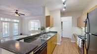Located in the Harbor Cove community of Houston, TX, this two-story, 2-bedroom, 3-bathroom home offers a well-organized layout spread across two levels. The main living area seamlessly combines the kitchen and living room, creating an open and functional space. The kitchen is equipped with dark granite-style countertops, warm wood cabinetry, a double-basin sink, black appliances including a refrigerator and range, a tiled backsplash, and track lighting overhead. A peninsula provides additional counter space and casual seating.

The living room is a standout feature, boasting an elegant tray ceiling with crown molding, a ceiling fan, and French doors that invite natural light and provide outdoor access. An arched window accent adds architectural charm to the space.

Both bedrooms are carpeted and include ceiling fans, with the primary bedroom offering a walk-in closet and a private bathroom featuring a wide vanity with wood cabinetry and a separate shower. Additional bathrooms include a tiled shower-tub combination. The second bedroom benefits from a large window with natural views.

The attached garage includes built-in wire shelving for added storage. The home's neutral palette and classic architectural details create a clean, cohesive ambiance throughout.