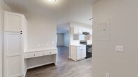Located in Lakeville, MN, this two-story, 3-bedroom, 2-bathroom home offers a well-organized layout spread across two floors. The main level features a combined kitchen and living area with an open pass-through design. The kitchen is equipped with white shaker-style cabinetry, black appliances including a refrigerator, range, and dishwasher, a single-basin sink, and durable wood-look vinyl plank flooring. A built-in desk area adds a practical workspace near the kitchen. The living room extends naturally from the kitchen, bathed in natural light from nearby windows. A half-bathroom on the main level features a white vanity with dark hardware and wood-look flooring. Upstairs, three bedrooms provide comfortable retreats, each with plush carpet, neutral paint tones, and windows that bring in natural light. The generously sized primary bedroom includes dual closets with white bifold doors. The upper-level bathroom features tile flooring, white cabinetry, and hallway access. Additional spaces include a laundry room, utility room, multiple closets for ample storage, and two staircases. Textured ceilings are present throughout, complementing the clean, neutral palette that gives the home a bright, move-in-ready feel.