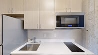 Located in the heart of downtown Milwaukee at 740 N Plankinton Ave, this efficiently designed 2-bedroom, 1-bathroom unit offers a thoughtful layout across a single floor. Wood-style plank flooring runs throughout the living spaces, lending warmth and visual continuity to the interior.

The kitchen is outfitted with light wood cabinetry, white quartz countertops, a stainless steel sink, a built-in electric cooktop, an over-the-range microwave, and a full-size stainless steel refrigerator — providing a complete set of modern appliances within a compact footprint.

The living area flows naturally from the kitchen, offering an open, flexible space with clean white walls. The primary bedroom is an intimate yet functional room, while the second bedroom features a large window framing direct views of Milwaukee's downtown skyline and surrounding historic architecture, filling the room with natural light.

The bathroom is finished with a full soaking tub and shower combination, complete with built-in corner shelving and chrome fixtures, set against bright white surrounds.

Throughout the unit, neutral tones, clean lines, and contemporary finishes create a cohesive, modern aesthetic well-suited to urban living in Milwaukee's vibrant downtown district.