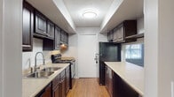 This single-floor residence offers a practical and comfortable layout designed for everyday living. The galley-style kitchen is a functional highlight, featuring dark espresso cabinetry with ample storage, light countertops, black appliances including a gas range and refrigerator, a double stainless steel sink, and warm wood-look flooring. A pass-through window connects the kitchen to the main living area, enhancing the sense of openness between spaces.

The spacious living room is anchored by a classic fireplace with a white surround, creating a welcoming focal point. Plush wall-to-wall carpeting, neutral gray walls, and a textured ceiling carry throughout the common areas, while a large window invites natural light and outdoor views into the space.

Two generously sized bedrooms each feature soft carpeting, ceiling fans with integrated lighting, and windows that allow for natural light. Both rooms offer ample space for comfortable furnishings.

The residence includes two full bathrooms, each outfitted with a tub-shower combination, a single-sink vanity with dark wood cabinetry, light countertops, a framed mirror, and wood-look flooring. The consistent finishes across both bathrooms contribute to a cohesive aesthetic throughout the home.