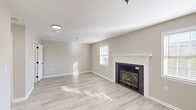 Located at 5 Spring Lane, this efficiently designed single-floor unit offers a well-planned layout comprising a living room, kitchen, bathroom, and two closets. The living room serves as the centerpiece of the space, featuring light wood-style flooring, neutral warm-toned walls, and a classic fireplace with a dark brick surround and a clean white mantel. Multiple windows allow natural light to fill the room, creating a bright and welcoming atmosphere throughout the day. The open layout connects the living area seamlessly to the kitchen, which is outfitted with a full suite of stainless steel appliances, including a refrigerator, range, over-the-range microwave, and dishwasher. White cabinetry with sleek dark hardware provides ample storage, while the light countertops and a single-basin sink add a clean, contemporary finish. A dedicated dining area adjacent to the kitchen benefits from a large bay window, further enhancing the natural light in the space. The bathroom features a full tub-shower combination with chrome fixtures and a sliding barn-style door. Consistent light wood-style flooring flows throughout, tying the entire space together with a cohesive, modern aesthetic.