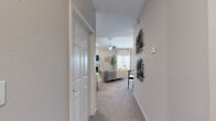 Located in Overland Park, Kansas, this 2-bedroom, 2-bathroom residence offers a thoughtfully designed single-floor layout that balances comfort and functionality. The living room serves as the heart of the home, featuring vaulted ceilings, a ceiling fan, plush carpeting, and a classic white-mantled fireplace framed by a large window that invites natural light. The space flows seamlessly into a dining area, creating an open and inviting atmosphere. The kitchen is outfitted with crisp white shaker cabinetry, stainless steel appliances, light wood-look flooring, and a peninsula with a built-in sink — ideal for both cooking and casual dining. The spacious primary bedroom boasts vaulted ceilings, a ceiling fan, soft carpeting, and direct access to an en-suite bathroom. The two bathrooms are well-finished, one featuring a walk-in glass shower and white cabinetry, the other a full tub-shower combo with a wide vanity and warm wood-tone flooring. A dedicated laundry room houses a full-size washer and dryer with shelving for added storage. Two closets provide ample organization throughout. The neutral color palette and consistent finishes lend the entire space a clean, modern aesthetic.