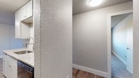 Located at 1010 S Chelton Rd in Colorado Springs, Colorado, this single-story unit offers a practical and functional layout designed for comfortable everyday living. The interior features wood-style plank flooring throughout the main living areas, providing a cohesive and easy-to-maintain surface underfoot. Textured walls and textured ceilings are consistent throughout, giving the space a classic residential character.

The living area is open and generously proportioned, offering a versatile space for furniture arrangement. It connects directly to the galley-style kitchen, which is equipped with white cabinetry providing ample storage, a single-basin sink, and black appliances including a refrigerator and electric range with overhead ventilation. The wood-style flooring continues into the kitchen, maintaining visual continuity.

The bedrooms are carpeted and each features a standard closet with a hanging rod, offering functional storage. The bathroom includes a full tub and shower combo with a white surround, brushed nickel fixtures, and wood-style flooring. Flush-mount ceiling lighting fixtures are present throughout, ensuring consistent illumination across all areas of the unit.