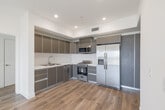 Located at 5801 W Pico Blvd in Los Angeles, this contemporary unit offers a thoughtfully designed open-concept layout with clean lines and a bright, modern aesthetic throughout. Warm hardwood-style flooring flows seamlessly across the living, dining, and kitchen areas, complemented by recessed lighting and crisp white walls that create an airy, welcoming atmosphere.

The kitchen is a standout feature, outfitted with sleek two-tone cabinetry in gray and taupe, white tile backsplash, light countertops, and a full suite of stainless steel appliances including a gas range, built-in microwave, dishwasher, and side-by-side refrigerator. A dedicated wet bar area with upper cabinetry and a sink adds additional functionality.

The spacious bedroom offers generous wall space, a large sliding-door closet with built-in organizers, and a picture window framing sweeping views of the Los Angeles skyline and surrounding mountains. The primary bathroom features large-format tile, a walk-in shower with dual showerheads and penny tile flooring, while a second bathroom includes a tiled stall shower, toilet, and vanity. A private balcony extends the living space outdoors with open city views, rounding out this well-appointed urban residence.