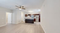 This thoughtfully designed 1-bedroom, 1-bathroom residence offers a cohesive single-floor layout that maximizes functionality and comfort. The open-concept living and kitchen area serves as the heart of the space, featuring light wood-style flooring and a ceiling fan that enhances airflow and comfort. A front entry door is framed by large windows fitted with blinds, filling the living area with natural light.

The kitchen is a standout feature, showcasing rich dark wood cabinetry, granite-look countertops, and a full suite of stainless steel appliances including a refrigerator, range, built-in microwave, and dishwasher. A built-in wine rack adds a stylish touch, while a central island with matching countertop provides additional prep space and casual dining potential. Pendant lighting above the island and recessed lighting complete the kitchen's polished look.

The bedroom offers a comfortable, carpeted retreat with two windows that invite natural light, a ceiling fan, and convenient access to both a closet and a hallway leading to the bathroom. The bathroom is clean and functional, featuring a full-size soaking tub and shower combination with built-in shelving and chrome fixtures. A hallway and dedicated closet round out the layout, providing practical storage solutions throughout the residence.