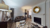 This single-floor residence combines contemporary design with refined finishes throughout its well-organized layout. The living room serves as a central gathering space, featuring a white-mantled fireplace, crown molding, wood-look flooring, and large windows dressed with grommet-panel curtains that allow natural light to filter through. A geometric-patterned area rug and mirrored accent furniture contribute to the room's polished aesthetic.

The dining area accommodates a round table with tufted upholstered chairs, situated beside bright windows that enhance the open feel of the space. The kitchen is outfitted with white cabinetry, granite countertops, a subway tile backsplash, and stainless steel appliances, including a range, microwave, and dishwasher.

The bedrooms are carpeted and thoughtfully designed. One features crown molding, wide windows, and star-burst wall décor, while another offers a more neutral, earthy palette with a low-profile dresser and framed artwork. A third bedroom space includes a decorative credenza with a mirrored accent mirror above.

Two bathrooms serve the residence — one with a soaking tub and tiled surround, the other featuring a white vanity with quartz-style countertop, wood-look flooring, and contemporary wall art.