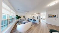 Located at 20 Maple Lane in Farmingville, NY, this well-designed single-story home offers a seamless blend of modern style and functional living across two bedrooms and two bathrooms. The open-concept layout connects the living room, dining area, and kitchen into one cohesive, light-filled space. Large windows flood the living area with natural light, while a ceiling fan adds comfort overhead. Light wood-tone flooring runs throughout the main living areas, creating a clean, cohesive aesthetic.

The kitchen is a standout feature, showcasing white shaker cabinetry, a classic subway tile backsplash, quartz countertops, and a full suite of stainless steel appliances including a gas range, microwave, and refrigerator. A kitchen island with bar seating provides additional prep space and a casual dining option.

The primary bedroom is generously sized, complete with a ceiling fan, a large window with neighborhood views, and access to a walk-in closet with built-in wire shelving. The second bedroom is equally bright and carpeted for added comfort. Both bathrooms are finished in crisp white tones — one features a sleek glass-enclosed walk-in shower, white vanity, and wood-look tile flooring. An attached single-car garage with an automatic opener rounds out this thoughtfully designed home.