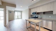 Located at 880 Pacific Street in Stamford, Connecticut, this well-appointed one-bedroom, one-bathroom residence offers a thoughtfully designed layout with modern finishes throughout. Light-toned hardwood-style flooring runs continuously across the entire unit, creating a cohesive and clean aesthetic.

The open-concept kitchen and living area serves as the heart of the unit. The kitchen features light wood cabinetry extending to the ceiling for maximum storage, a subway tile backsplash, stainless steel appliances including a gas range, microwave, and French door refrigerator, and a freestanding island that provides additional prep and dining space. The living area flows naturally from the kitchen, bathed in natural light from a large sliding glass door that opens onto a private balcony with views of the surrounding Stamford skyline.

The spacious bedroom also benefits from floor-to-ceiling windows, allowing abundant natural light and framing urban views. A hallway connects the main living spaces to three closets, offering generous storage. The full bathroom is finished with a backlit vanity mirror, an undermount sink set in a sleek countertop, taupe cabinetry, and a tub-shower combination with white tile surround. A dedicated in-unit laundry area adds everyday convenience, completing this modern urban residence.