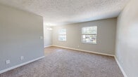 Located at 1512 E 10th St in Jeffersonville, Indiana, this single-floor, two-bedroom, one-bathroom home offers a functional and well-maintained layout. The living area features soft carpeting, neutral gray walls, and a textured ceiling, with multiple windows that invite natural light and views of the surrounding greenery. A chandelier adds a subtle decorative touch to the open living and dining space, which transitions to hardwood-style flooring toward the kitchen.

The galley-style kitchen is well-appointed with white shaker cabinets, granite countertops, a stainless steel sink, and wood-look flooring. Black appliances, including a full-size refrigerator and range, complete the space, while overhead fluorescent lighting keeps the area bright.

Both bedrooms are carpeted and painted in soft, neutral tones, each featuring windows with blinds that allow natural light to filter in. The primary bedroom offers a comfortable footprint, a closet, and easy access to the hallway and shared spaces.

The full bathroom is clean and efficient, featuring a tiled tub-shower combo, a white vanity with granite countertop, wood-look flooring, and a drop ceiling with panel tiles. A dedicated closet and hallway provide additional storage and connectivity throughout the home, making this a practical and move-in ready residence.